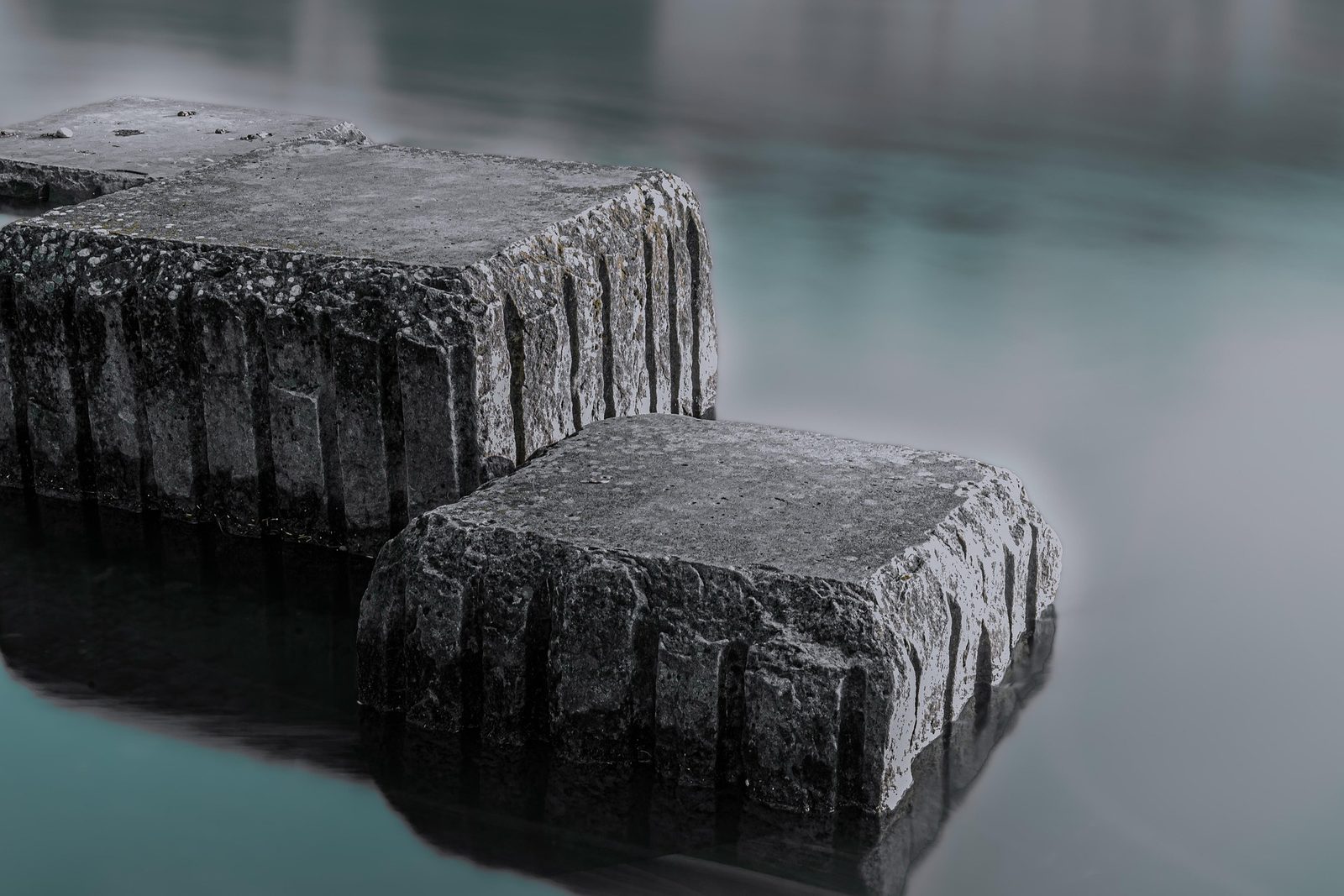 Two square stone blocks rising from still water like stepping stones