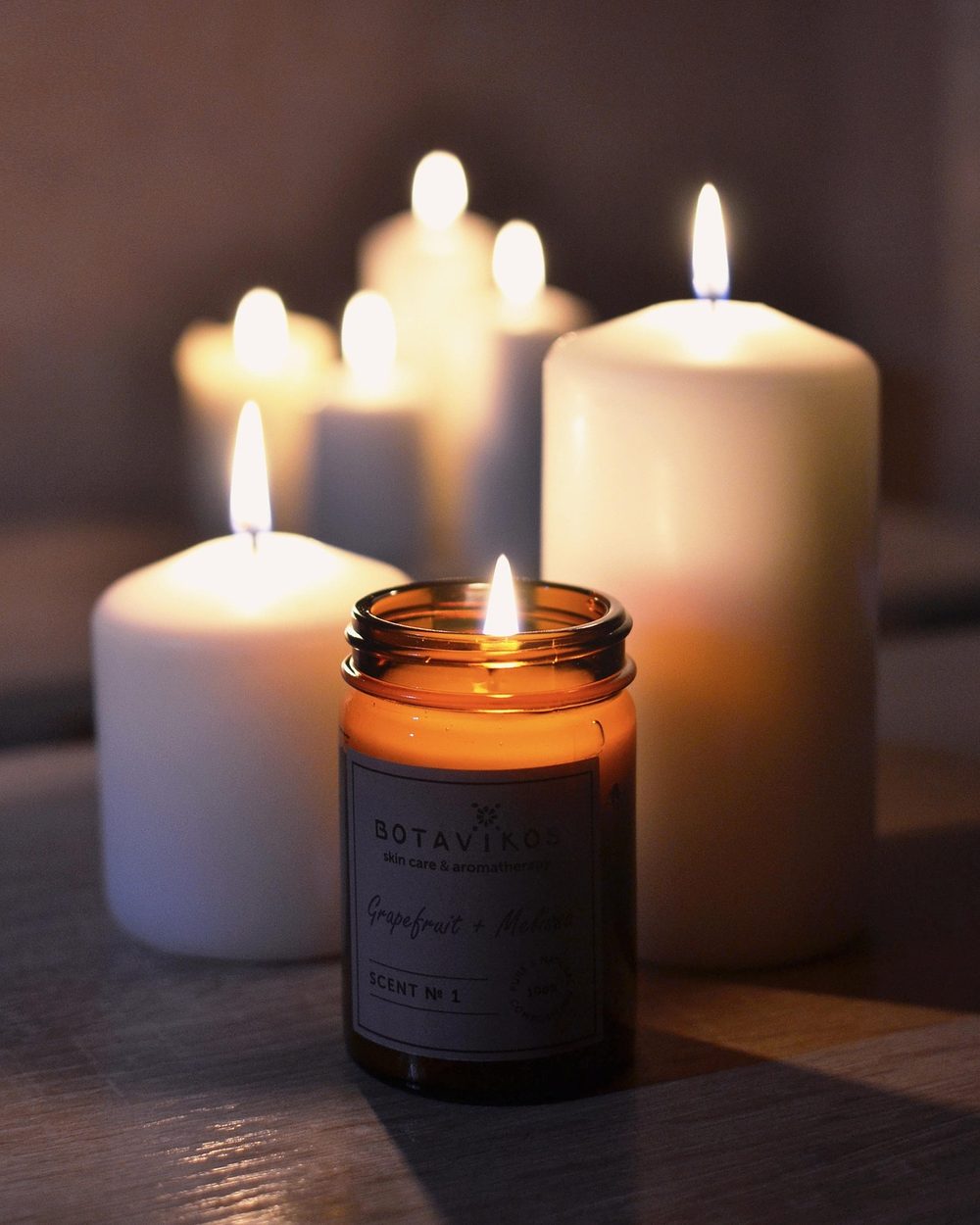 Lit pillar candles and a candle in a glass jar in a dim, quiet room