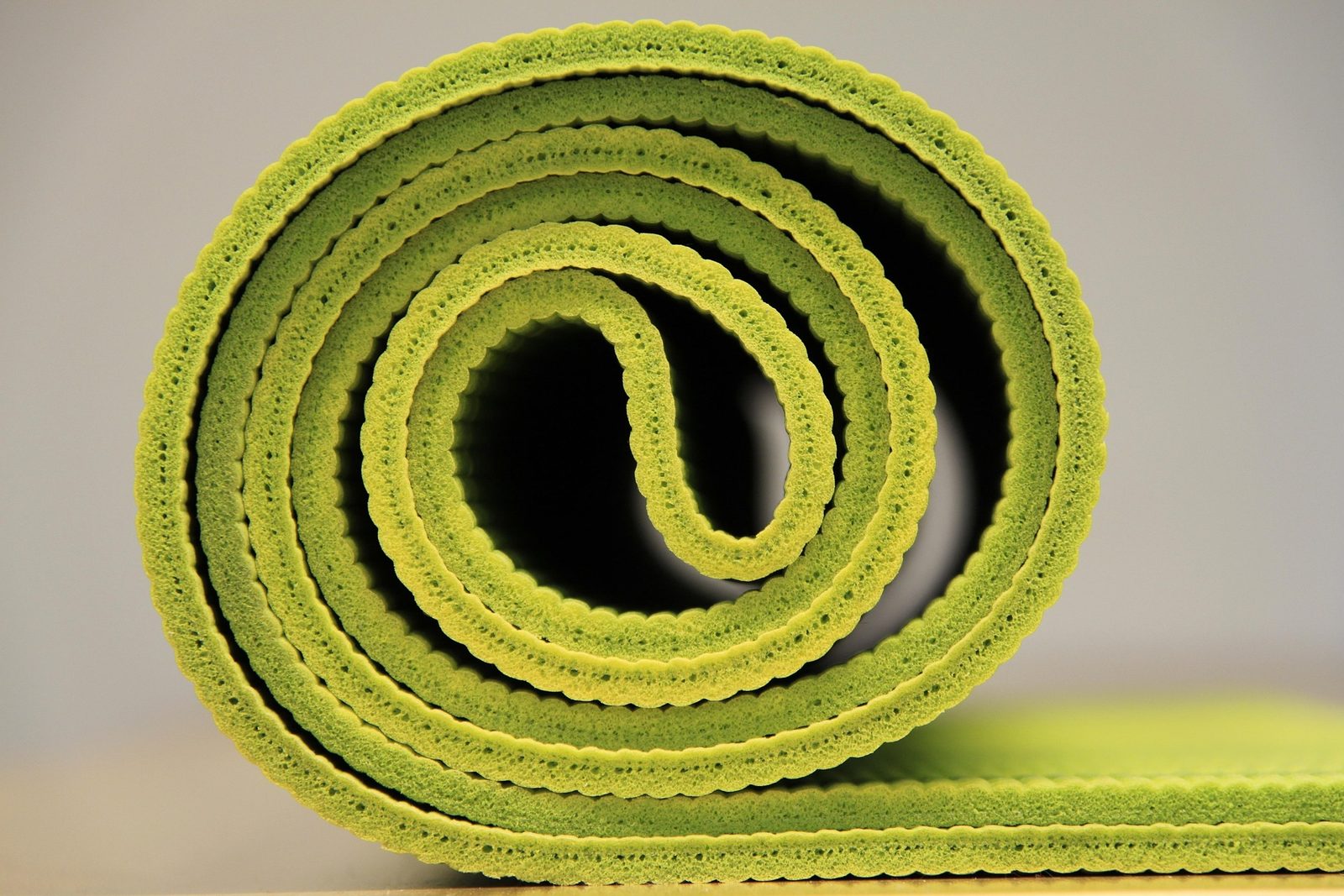 A green yoga mat rolled up on the floor